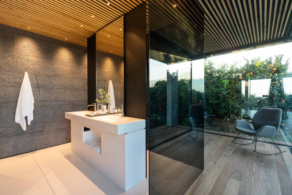 Ispirazione per una stanza da bagno moderna con ante bianche, piastrelle grigie, pavimento in legno massello medio, lavabo a consolle e pavimento marrone