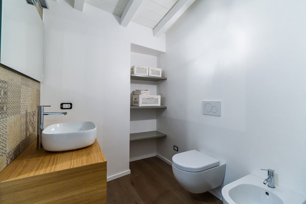 Design ideas for a modern shower room bathroom in Milan with medium wood cabinets, a bidet, white walls, dark hardwood flooring, a vessel sink, wooden worktops and brown floors.