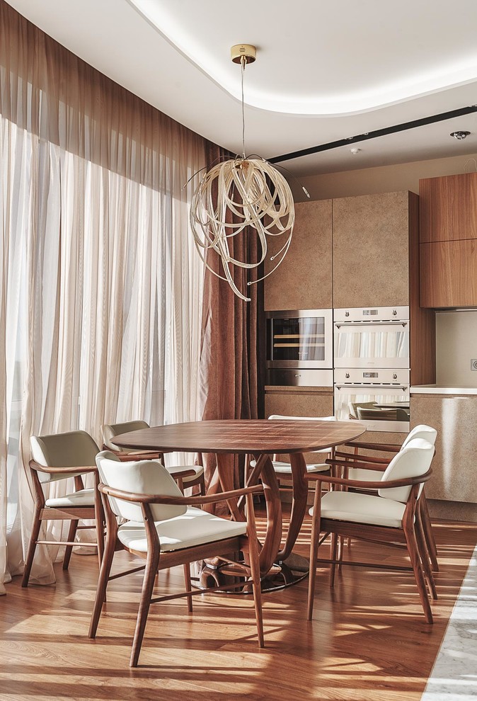 Cette image montre une salle à manger ouverte sur la cuisine design avec un sol en bois brun.