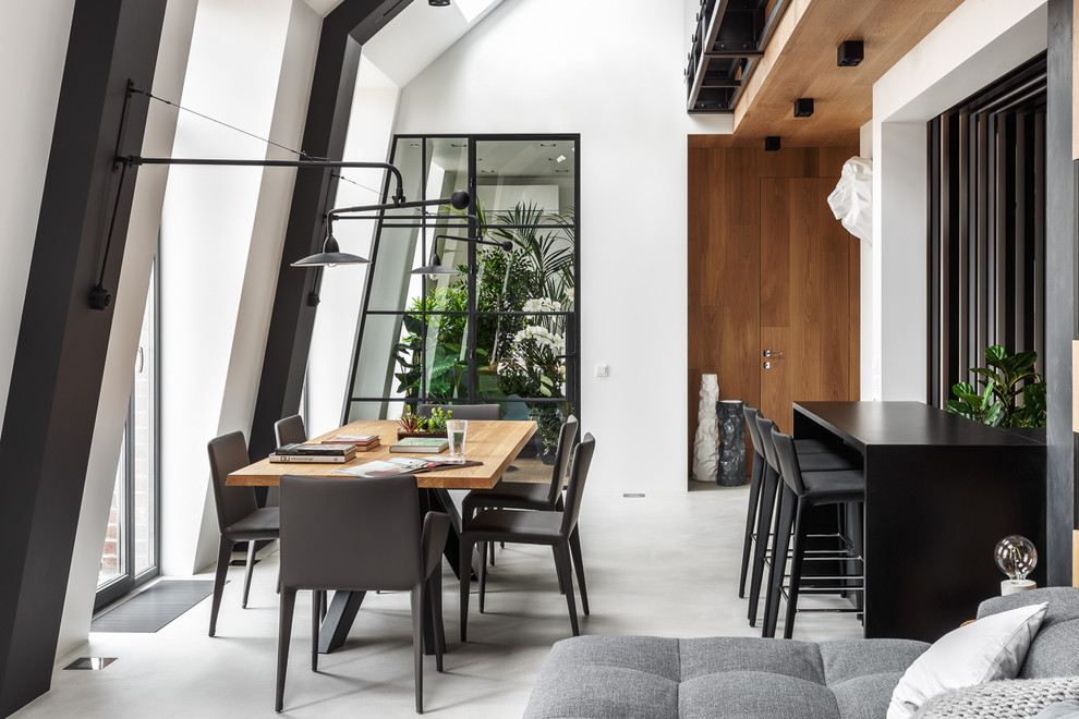 Immagine di una sala da pranzo aperta verso il soggiorno design di medie dimensioni con pareti bianche, pavimento in cemento e pavimento grigio