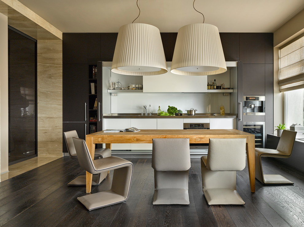 На фото: кухня-столовая в современном стиле с бежевыми стенами и темным паркетным полом с