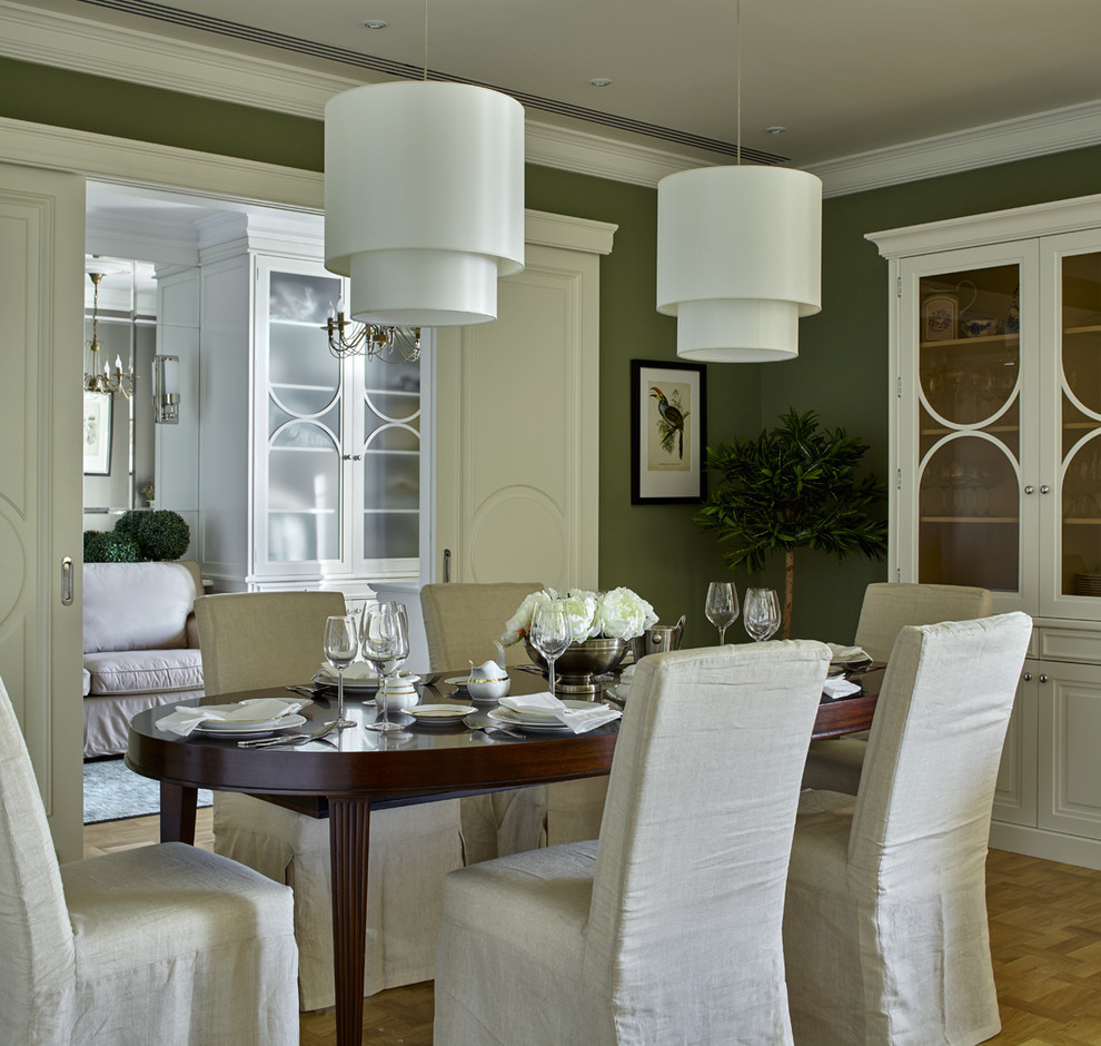 На фото: столовая в классическом стиле с зелеными стенами и паркетным полом среднего тона