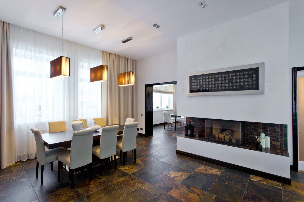 Foto de comedor contemporáneo con paredes blancas, marco de chimenea de baldosas y/o azulejos y todas las chimeneas