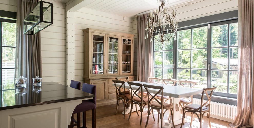 Réalisation d'une salle à manger ouverte sur la cuisine tradition avec un mur blanc et un sol en bois brun.