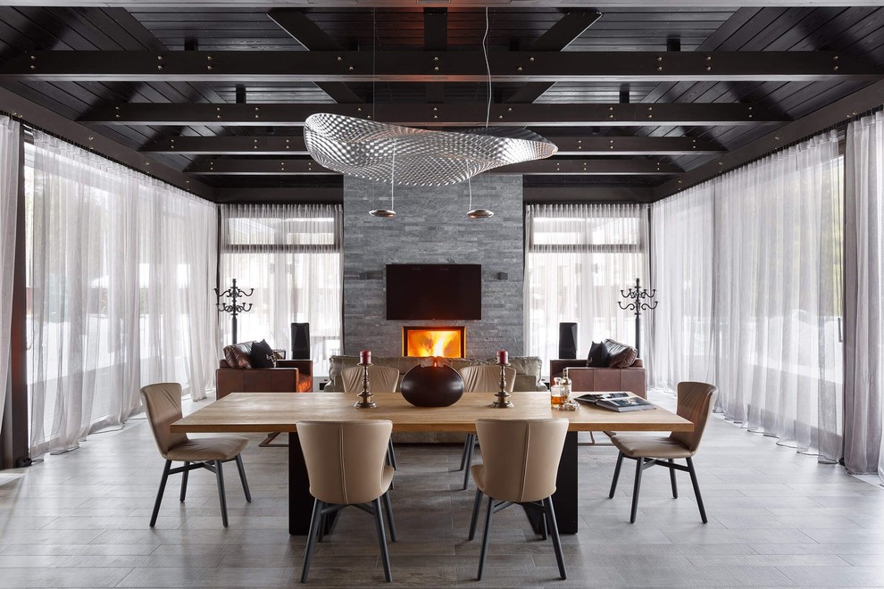 На фото: гостиная-столовая в современном стиле с стандартным камином и серым полом с