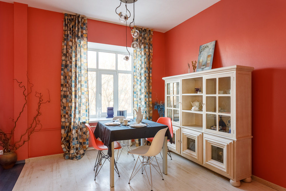 Cette image montre une salle à manger ouverte sur le salon bohème avec un mur rouge, parquet clair et un sol beige.