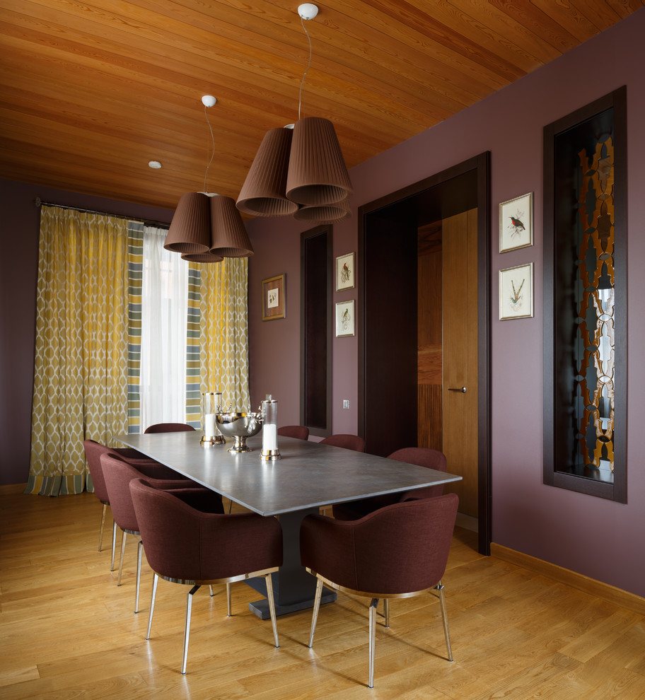 Aménagement d'une salle à manger contemporaine avec un mur violet et un sol en bois brun.