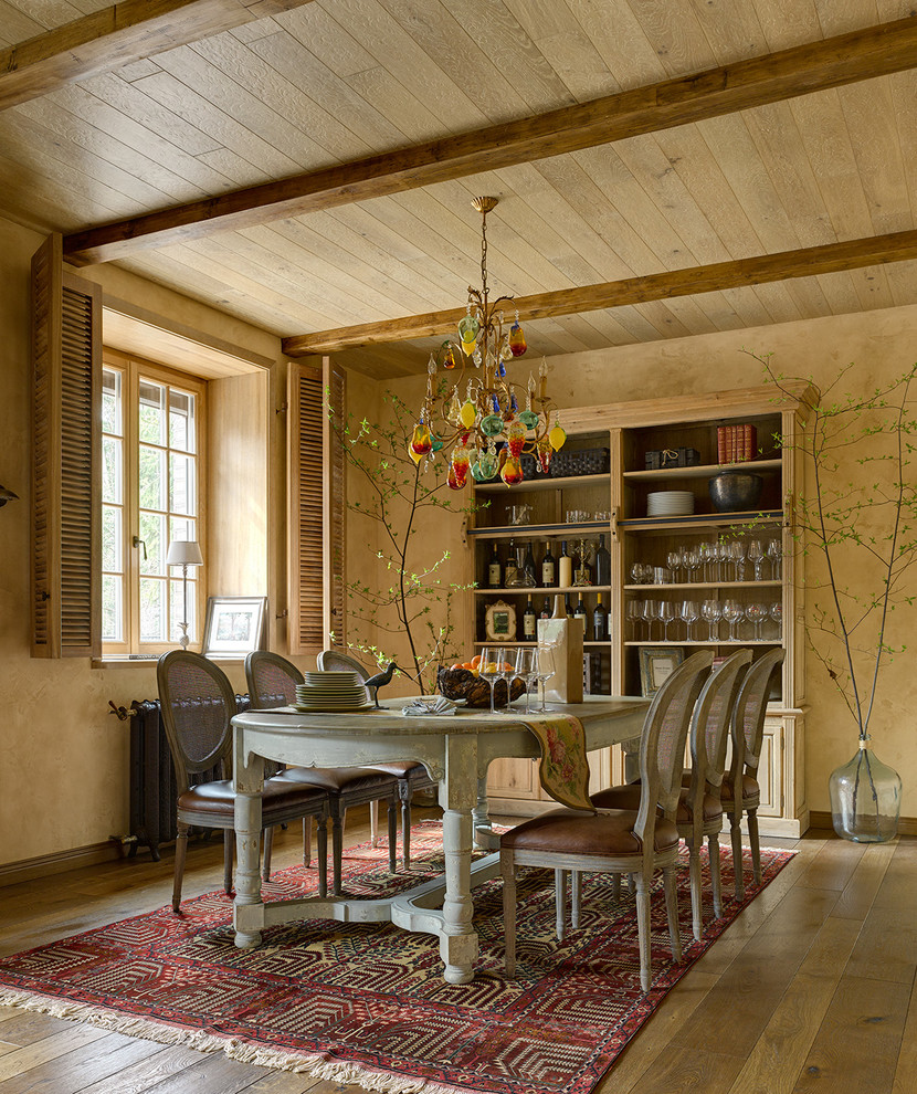Immagine di una sala da pranzo mediterranea con pareti beige, pavimento in legno massello medio e nessun camino
