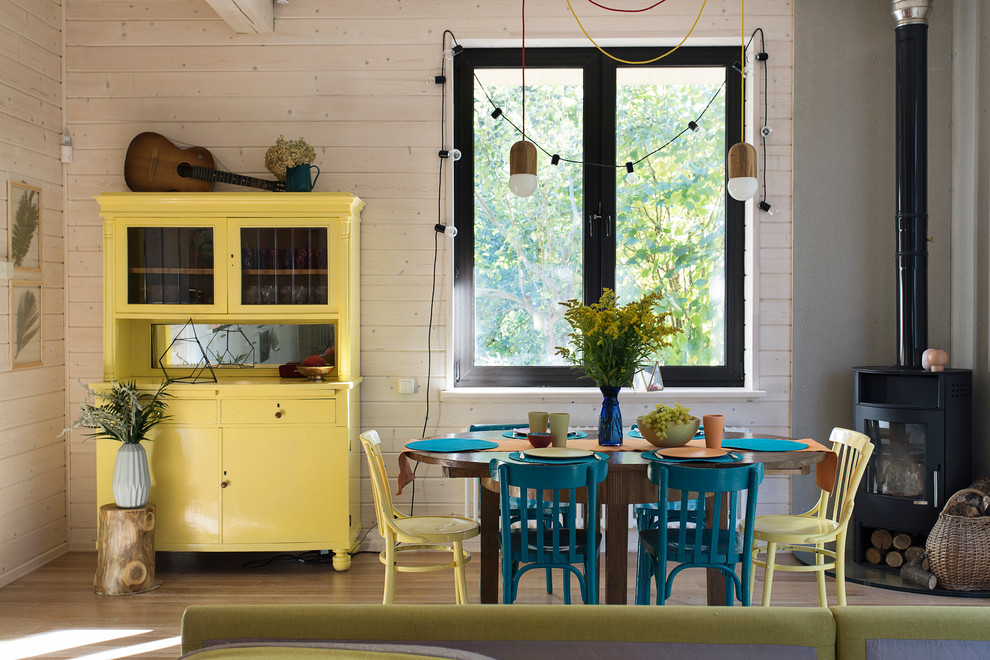 Foto de comedor contemporáneo con paredes beige, suelo de madera clara y estufa de leña