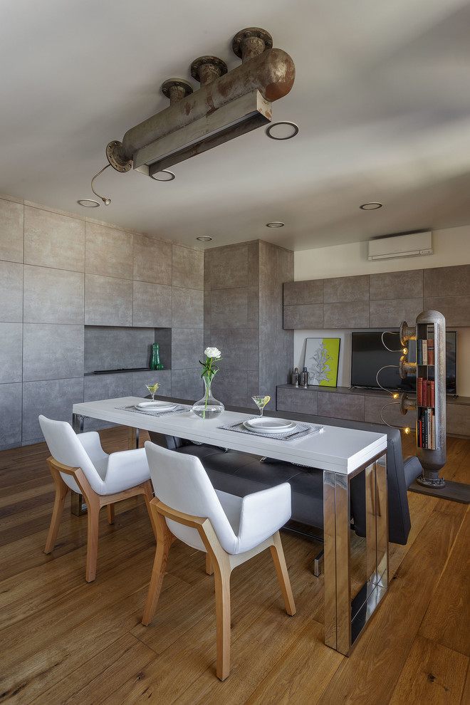 Immagine di una sala da pranzo aperta verso il soggiorno industriale di medie dimensioni con pareti grigie, camino lineare Ribbon, pavimento marrone e pavimento in legno massello medio