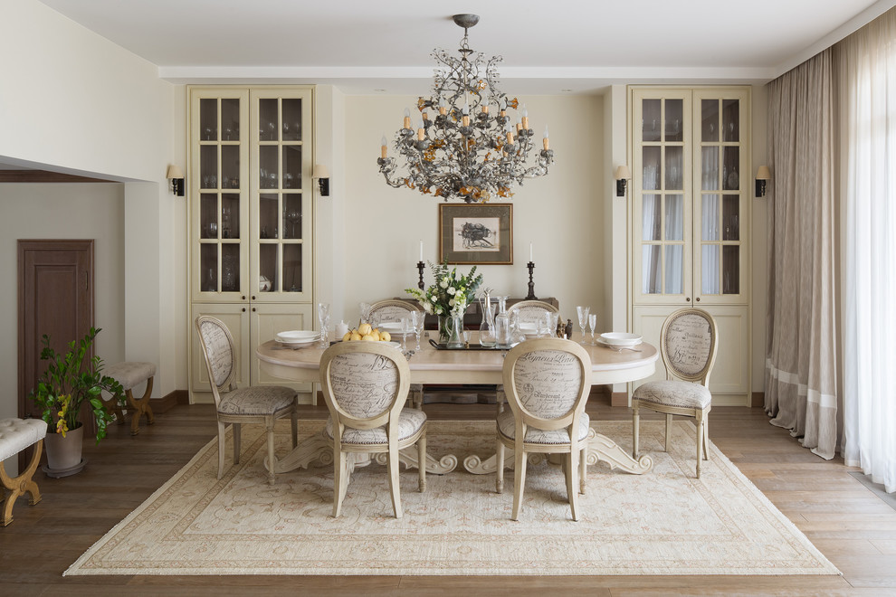 This is an example of a classic dining room in Moscow with white walls, medium hardwood flooring and brown floors.