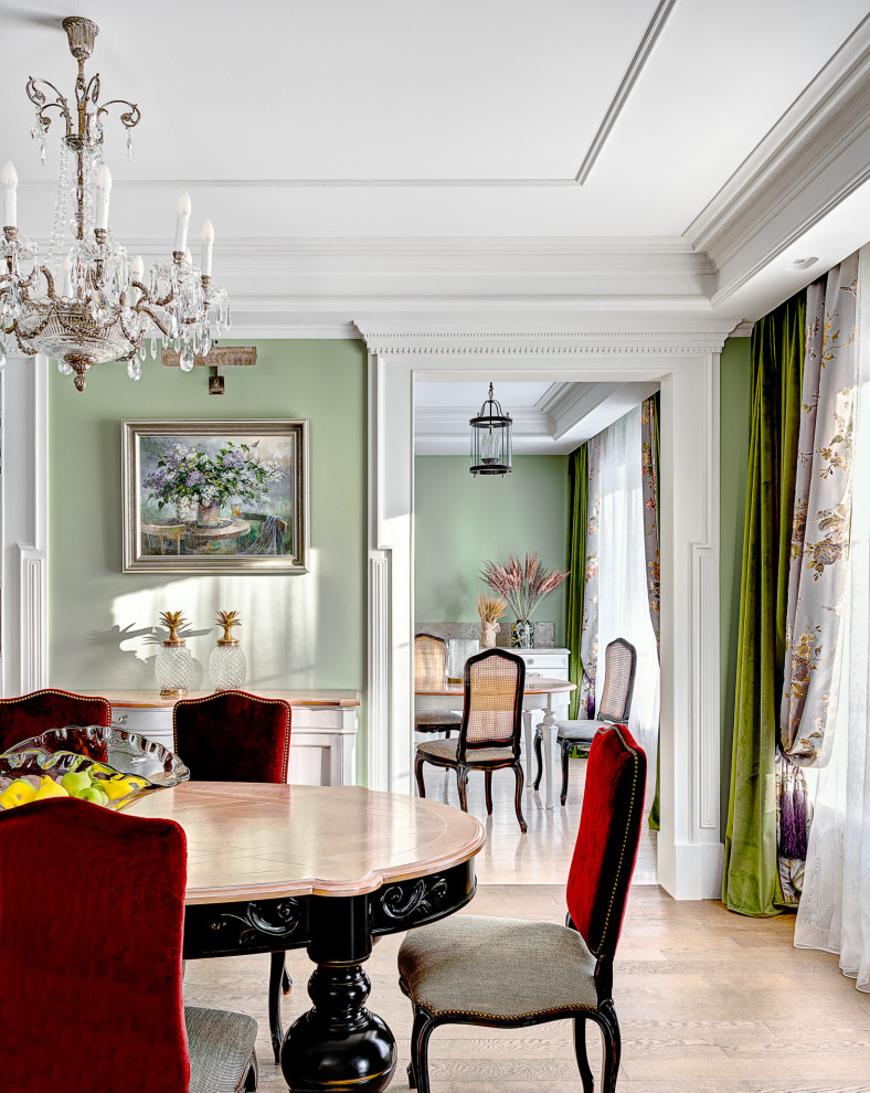 На фото: столовая в классическом стиле с зелеными стенами, светлым паркетным полом и многоуровневым потолком с