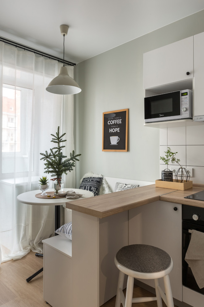 Skandinavisk inredning av ett kök med matplats, med ljust trägolv, beiget golv och grå väggar