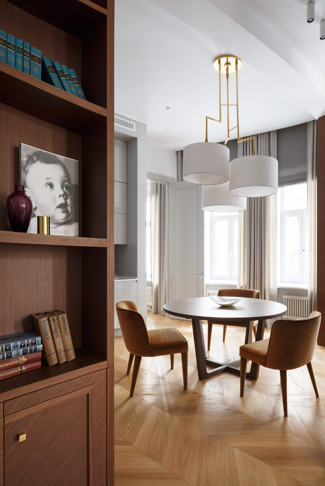 This is an example of a contemporary kitchen/dining room in Moscow with white walls and light hardwood flooring.