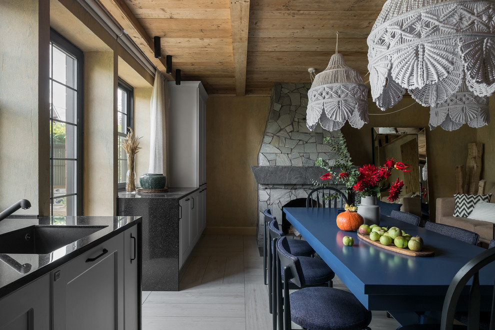 Стильный дизайн: кухня-столовая среднего размера в стиле рустика с бежевыми стенами, полом из керамогранита, стандартным камином, фасадом камина из камня и белым полом - последний тренд