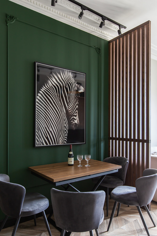 Réalisation d'une salle à manger design avec un mur vert, un sol en bois brun et un sol beige.
