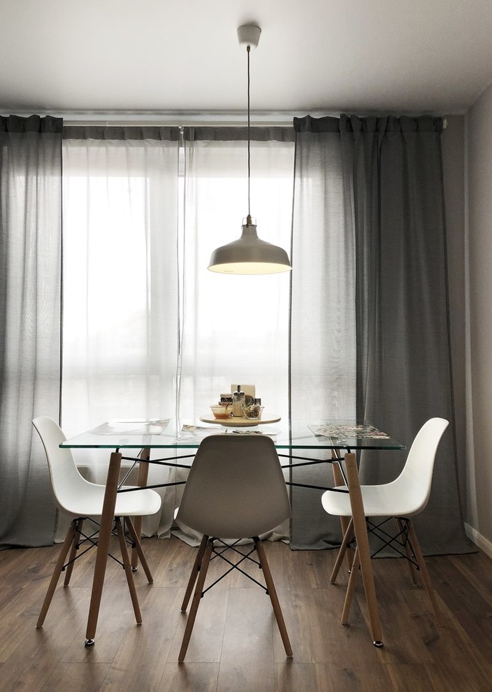 На фото: кухня-столовая среднего размера в скандинавском стиле с серыми стенами, полом из ламината и коричневым полом без камина с