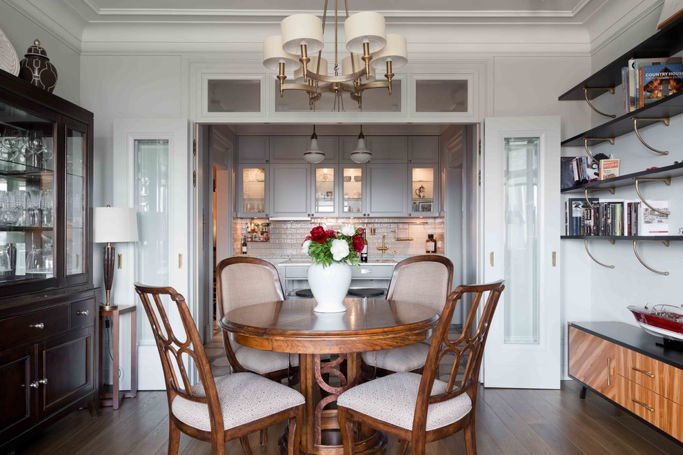 Immagine di una sala da pranzo aperta verso il soggiorno classica con pareti grigie e parquet chiaro