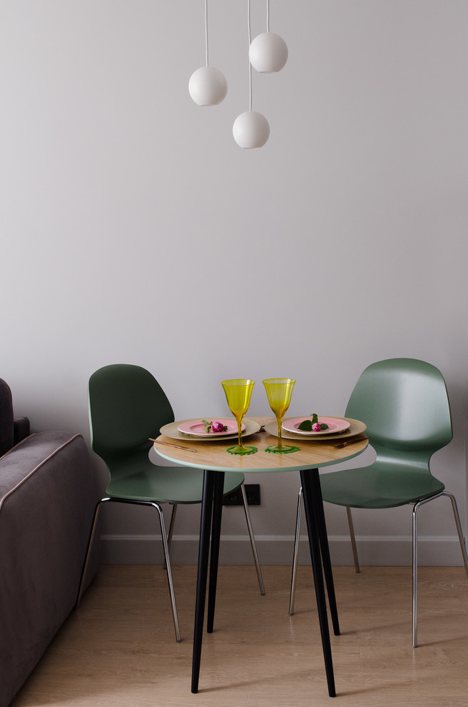 Стильный дизайн: маленькая гостиная-столовая в современном стиле с серыми стенами, полом из ламината и коричневым полом для на участке и в саду - последний тренд