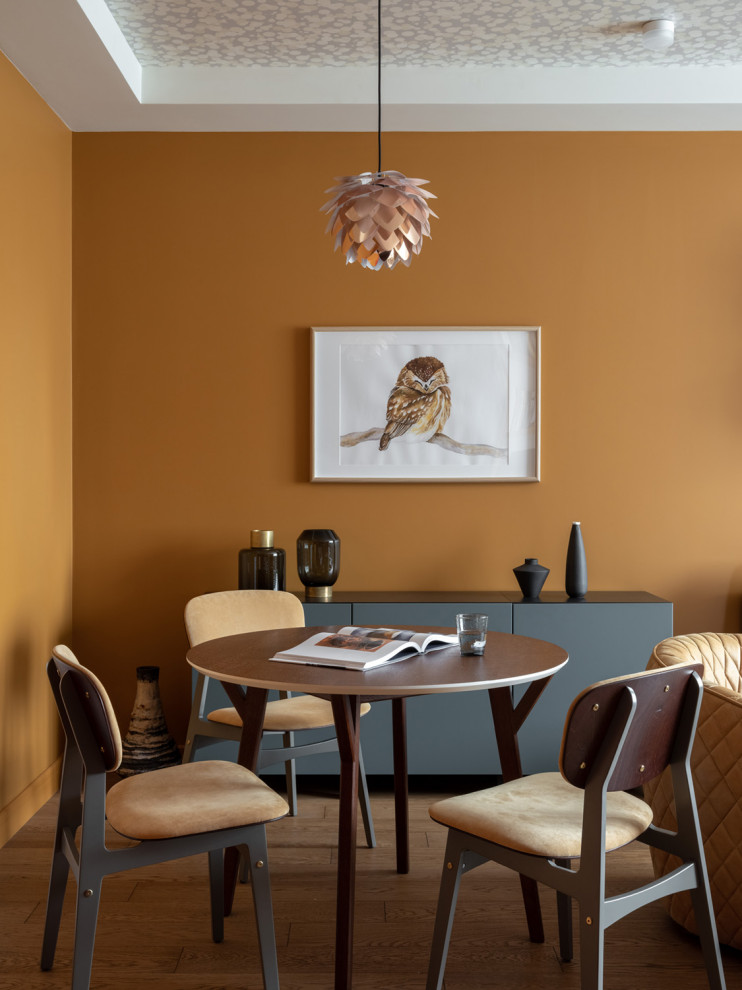 Aménagement d'une salle à manger contemporaine avec un mur orange et un sol marron.