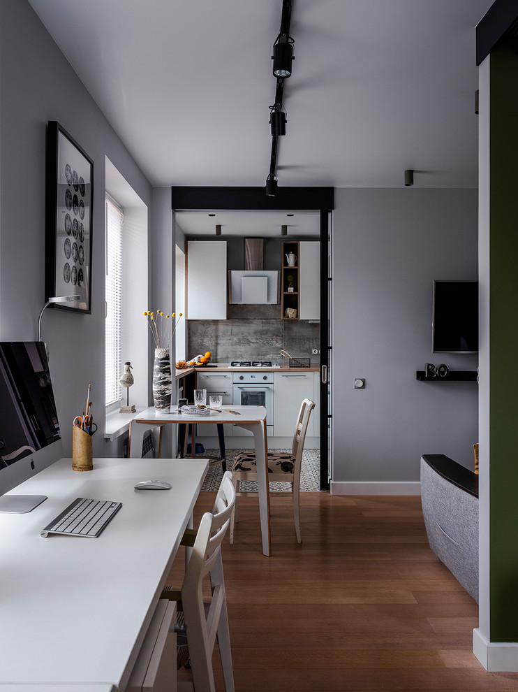 Aménagement d'une salle à manger ouverte sur le salon contemporaine avec un mur gris, un sol en bois brun et un sol marron.