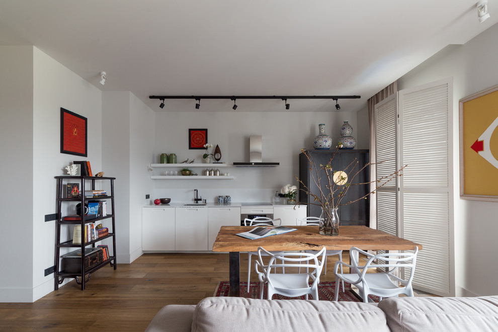 Cette image montre une salle à manger ouverte sur le salon design avec un sol en bois brun, un mur blanc et un sol marron.