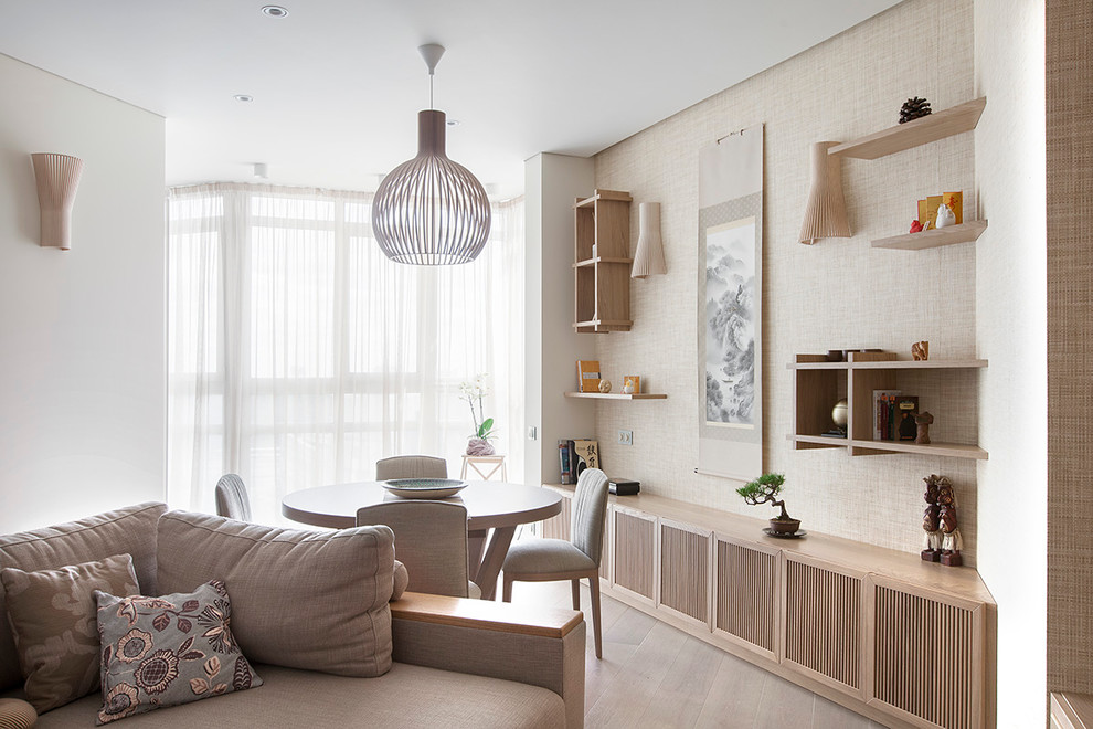 Foto di una sala da pranzo aperta verso il soggiorno minimal con pareti beige e parquet chiaro