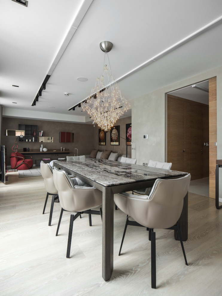 Immagine di una sala da pranzo aperta verso il soggiorno design con pareti grigie, parquet chiaro e pavimento beige