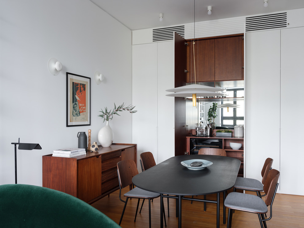 Foto di una sala da pranzo aperta verso il soggiorno moderna con pareti bianche, pavimento in legno massello medio e pavimento marrone