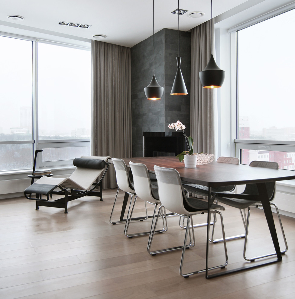 Пример оригинального дизайна: гостиная-столовая в современном стиле с светлым паркетным полом, фасадом камина из бетона и угловым камином