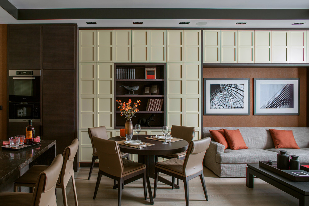 Aménagement d'une salle à manger ouverte sur le salon contemporaine avec un mur marron, parquet clair et un sol beige.