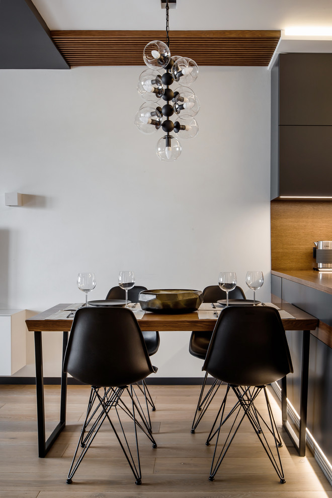 Ispirazione per una piccola sala da pranzo aperta verso la cucina minimal con pareti bianche e pavimento in legno massello medio