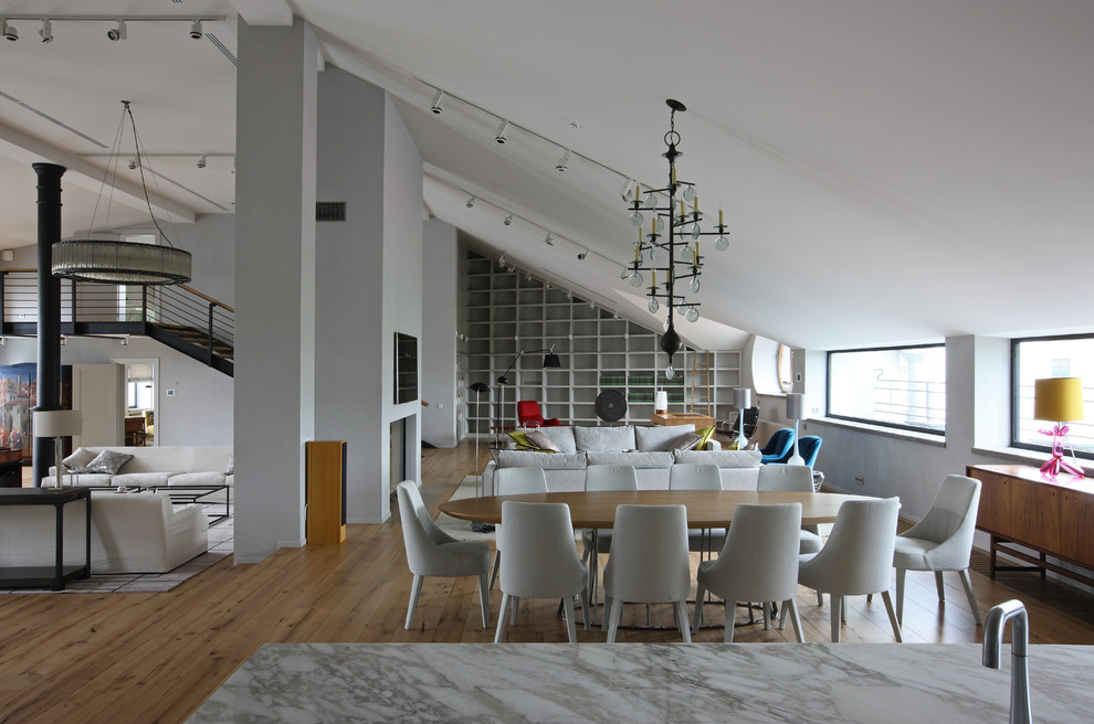 На фото: большая гостиная-столовая в стиле лофт с серыми стенами, двусторонним камином, фасадом камина из бетона и паркетным полом среднего тона