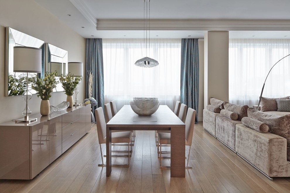 Immagine di una sala da pranzo aperta verso il soggiorno contemporanea con pareti beige, parquet chiaro e pavimento beige