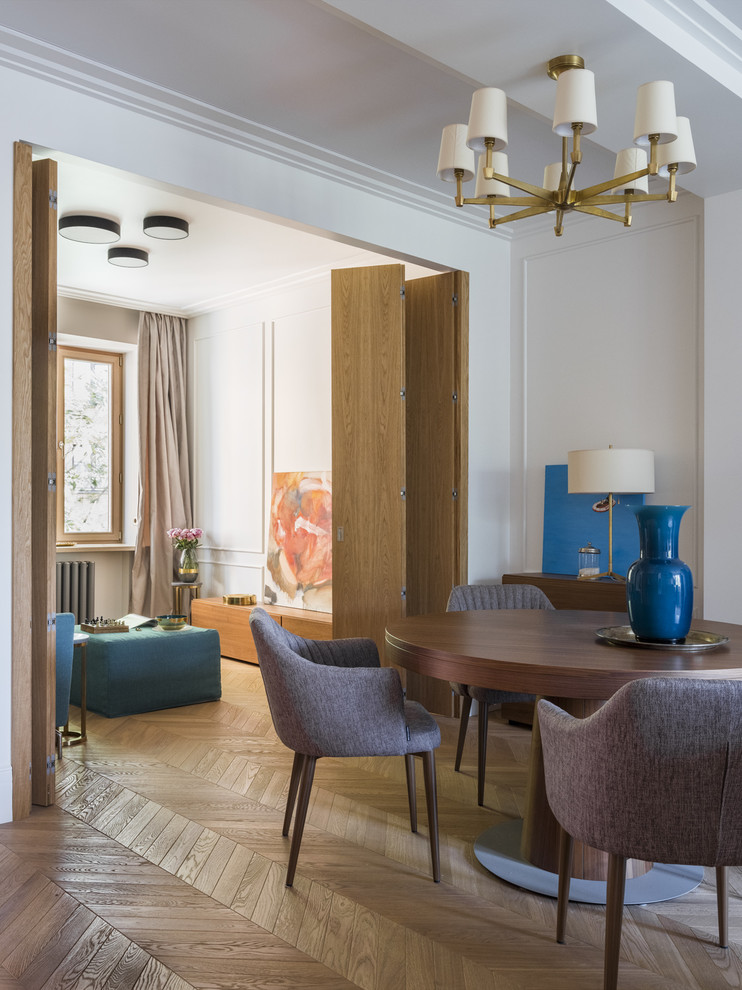 Idées déco pour une salle à manger ouverte sur le salon contemporaine avec un mur blanc, un sol en bois brun, un sol beige et éclairage.