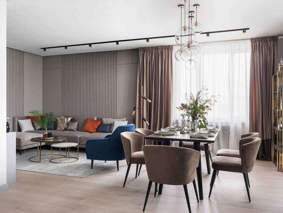 Immagine di una grande sala da pranzo aperta verso il soggiorno design con pareti grigie, parquet chiaro e pavimento beige