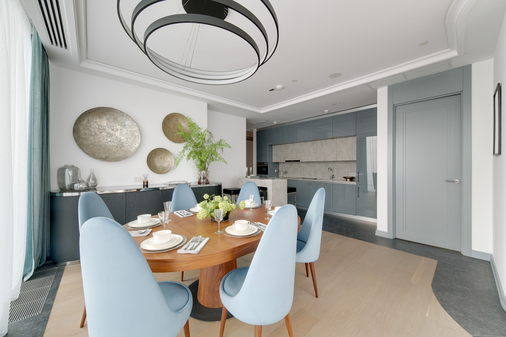 Cette photo montre une salle à manger ouverte sur la cuisine tendance de taille moyenne avec un mur blanc et un sol gris.