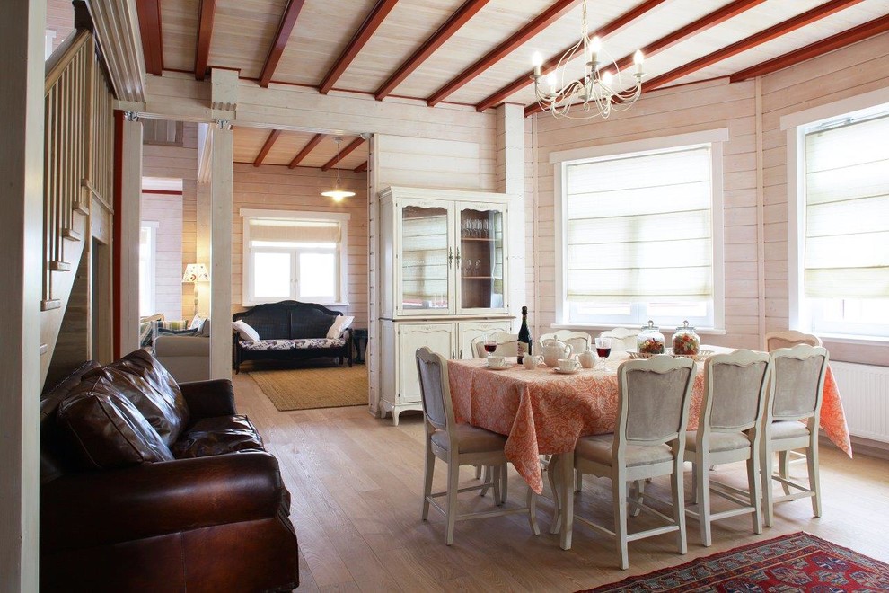 Immagine di una sala da pranzo aperta verso il soggiorno country con pareti bianche e parquet chiaro