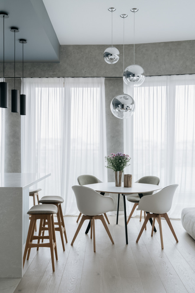 Exemple d'une salle à manger ouverte sur le salon tendance avec un mur gris, parquet clair, aucune cheminée et un sol beige.