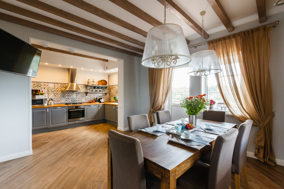 На фото: кухня-столовая в стиле кантри с серыми стенами и коричневым полом