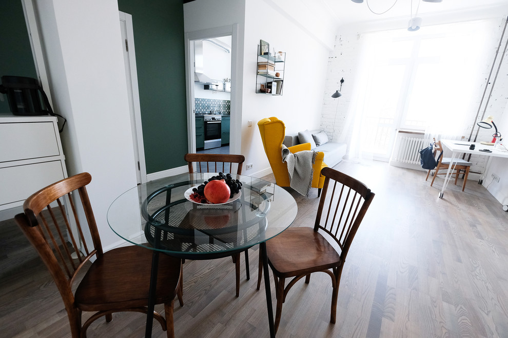 Cette image montre une salle à manger ouverte sur le salon nordique de taille moyenne avec un mur blanc, un sol en bois brun et un sol marron.