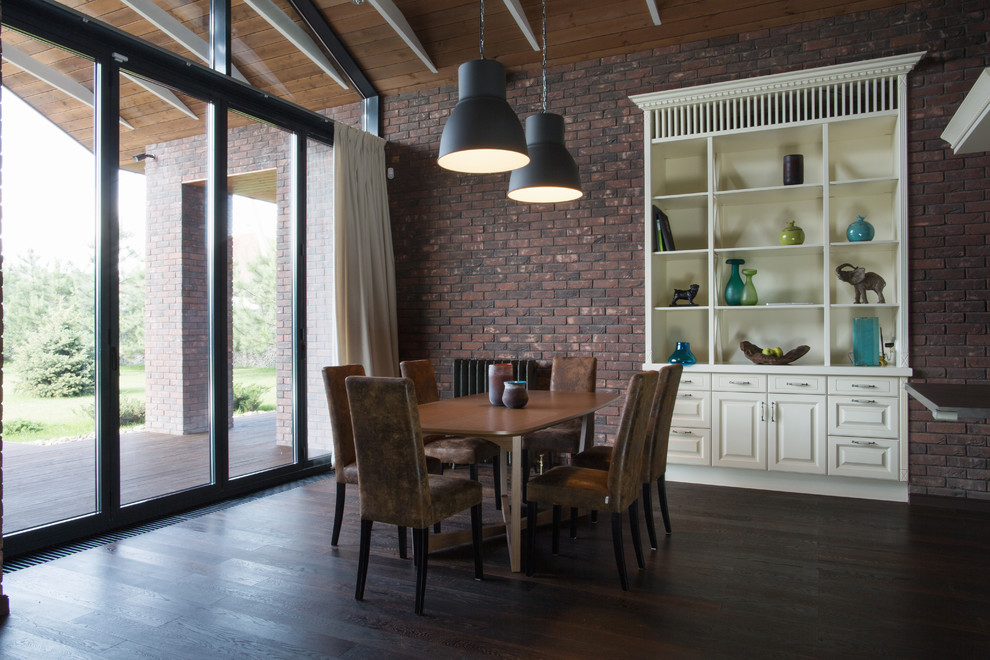 Источник вдохновения для домашнего уюта: огромная кухня-столовая в современном стиле с коричневыми стенами, полом из ламината, коричневым полом, двусторонним камином и фасадом камина из кирпича
