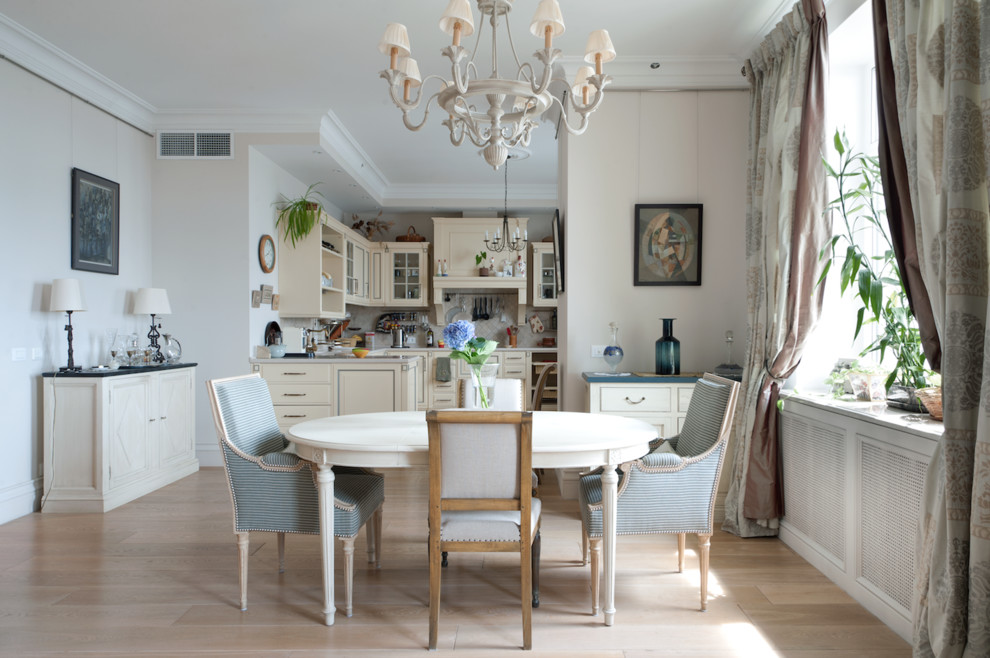 На фото: кухня-столовая в классическом стиле с белыми стенами и светлым паркетным полом с
