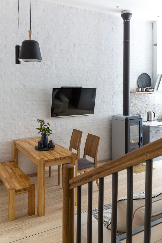 Cette image montre une salle à manger ouverte sur le salon design avec un mur blanc et parquet clair.