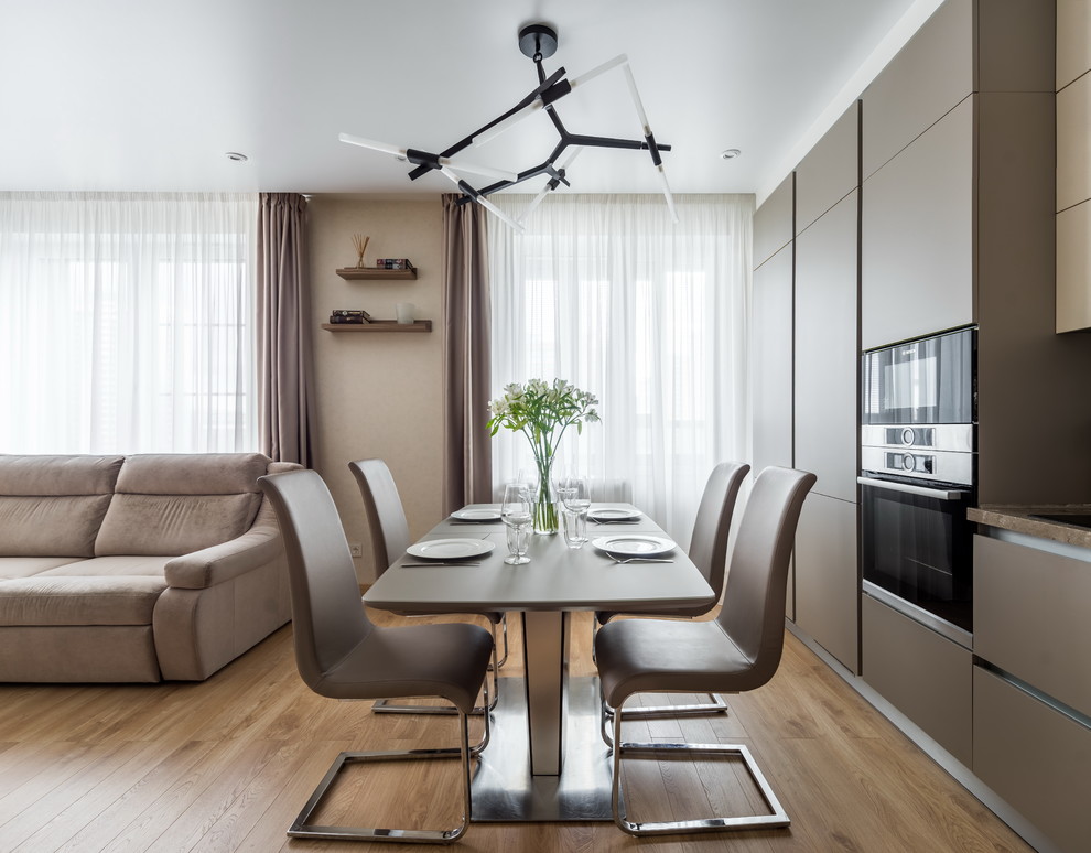 Idee per una sala da pranzo aperta verso il soggiorno minimal con pareti beige, pavimento marrone e pavimento in legno massello medio