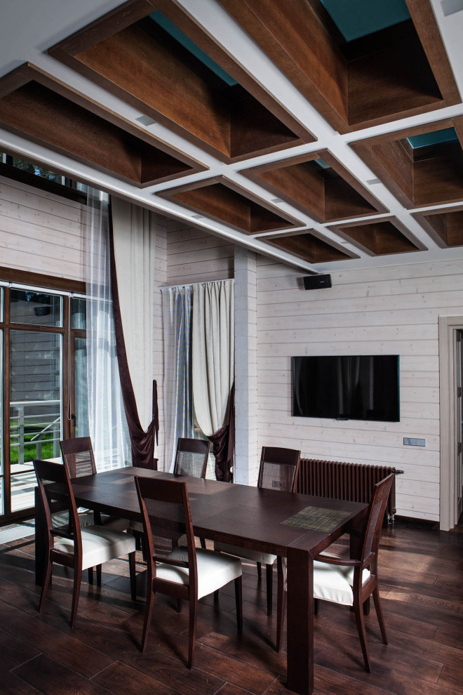 Cette image montre une grande salle à manger ouverte sur la cuisine design en bois avec un mur blanc, un sol marron et un plafond en bois.