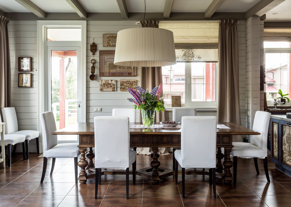 Inspiration pour une salle à manger ouverte sur la cuisine rustique avec un mur blanc et un sol marron.