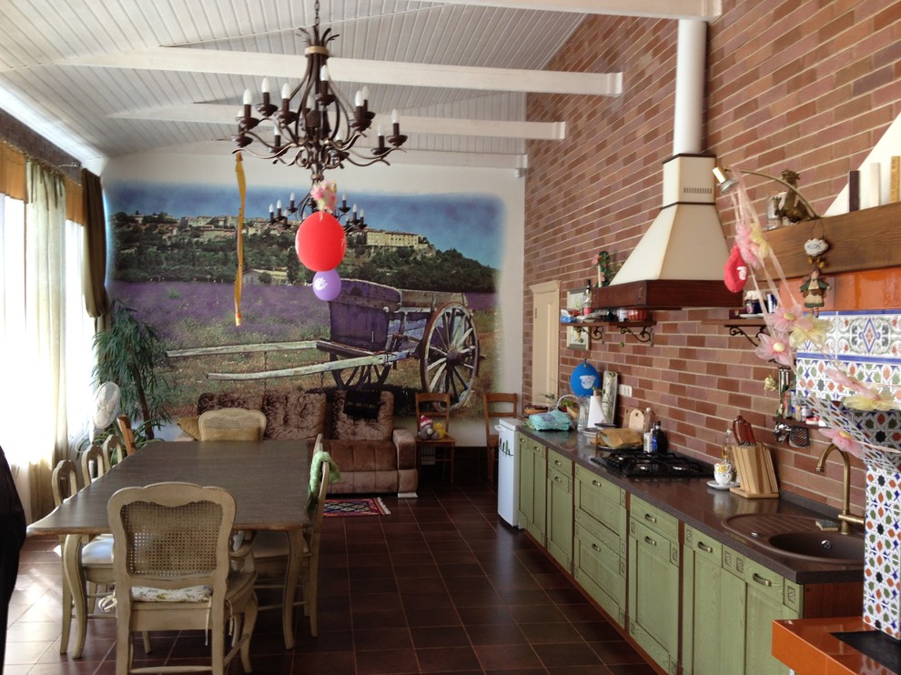 他の地域にある高級な中くらいなトラディショナルスタイルのおしゃれなダイニングキッチン (茶色い壁、セラミックタイルの床、標準型暖炉、タイルの暖炉まわり、茶色い床) の写真