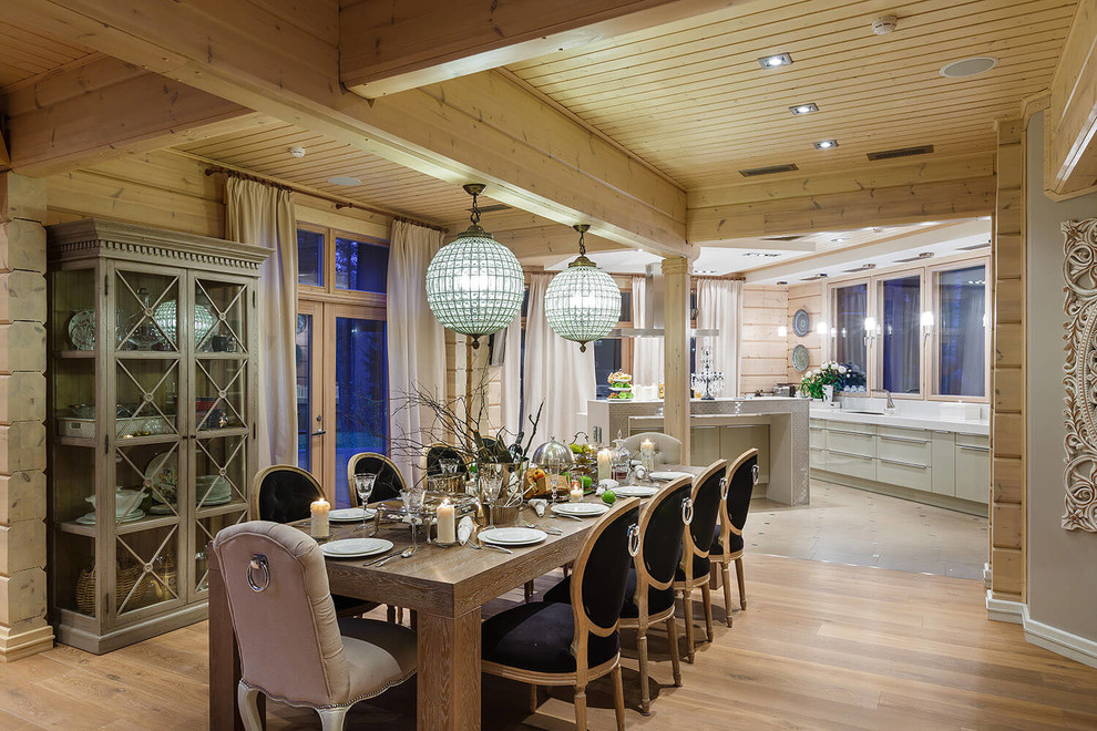 Cette image montre une salle à manger ouverte sur la cuisine chalet avec un mur beige et parquet clair.