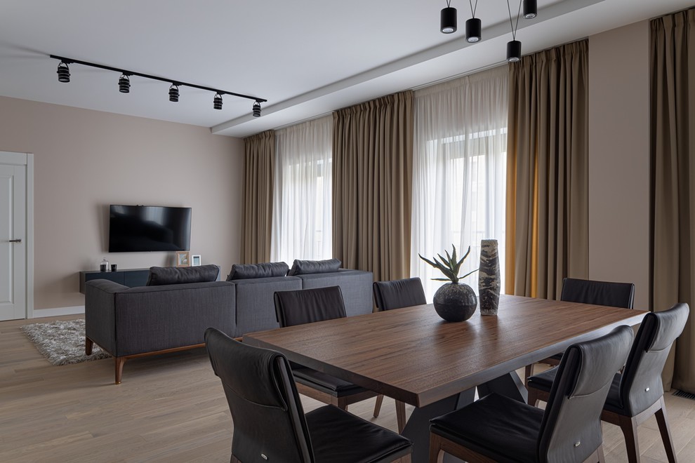 Immagine di una grande sala da pranzo aperta verso il soggiorno design con pareti beige, parquet chiaro e pavimento beige